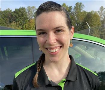 Girl smiling with brown hair wearing a black shirt in front of a green background.