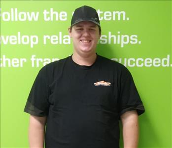 tall man in black shirt in front of a green wall