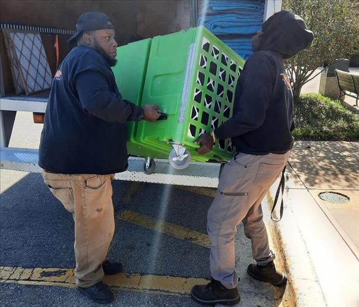 Two SERVPRO technicians unloading green equipment for restoration