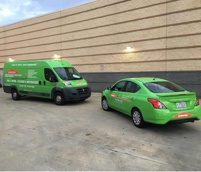 Two SERVPRO vehicles parked in front of a tan wall