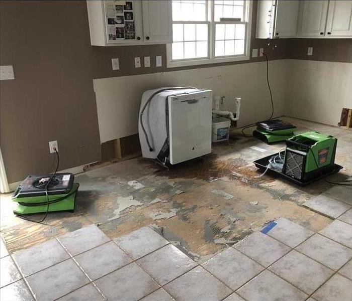 Floor has been removed from kitchen due to water damage, drying equipment settled in place