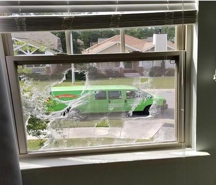 looking out of window of fire damaged home; SERVPRO vehicle parked outside