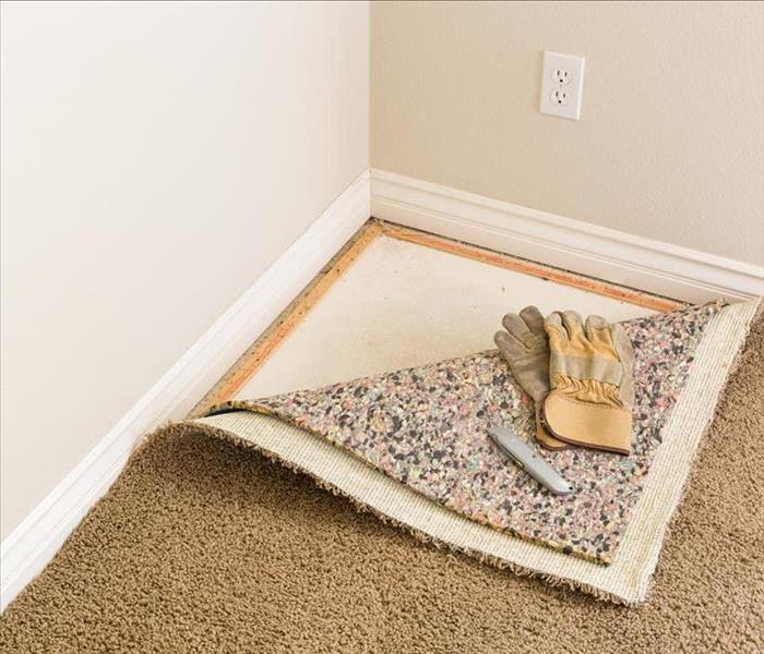 Carpet and padding pulled back from corner